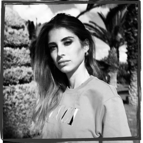 A woman w/shoulder-length, dark, highlighted hair looks at the camera with a smoky gaze