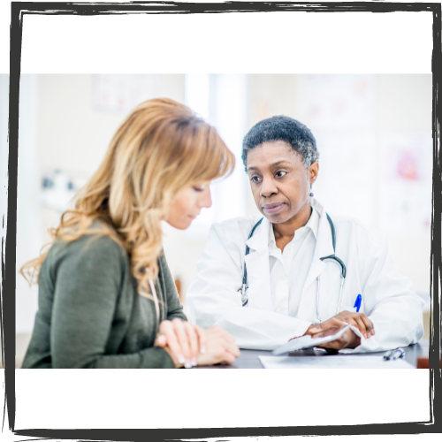 A Black woman doctor discusses a diagnosis w/a young woman w/long, blonde hair