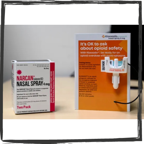 A small, white box printed in red "Narcan" and black "nasal spray" next to a taller orange container with a white, plastic fixture and in white "It's OK to ask about opioid safety"
