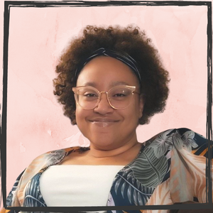 A smiling woman with short, curly, brown hair and peach-colored glasses