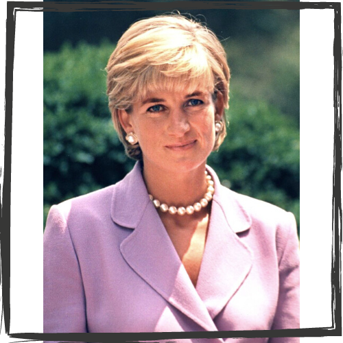 Photo of a white woman w/short, blonde hair wearing pearl earrings and necklace and a lavender suit