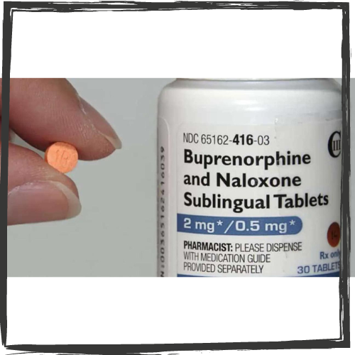 Photo of 2 fingers holding a small, orange pill to the left of a white bottle w/the label Buprenorphine