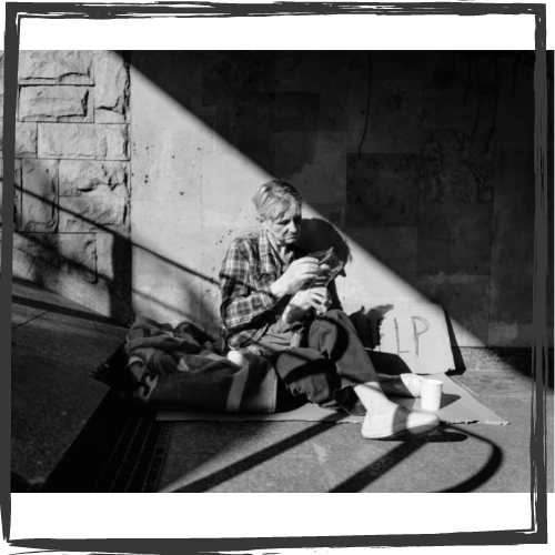 b&w photo of a short-haired, middle-aged, white woman sitting at the bottom of a stairway outside on a blanket