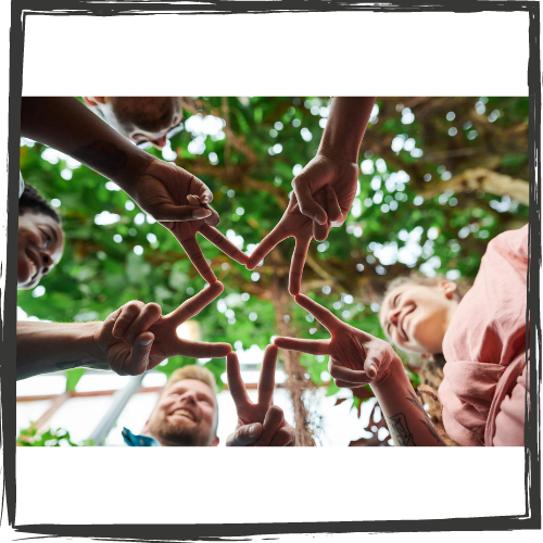 Photo of people standing in a circle holding up their fingers to make a star shape