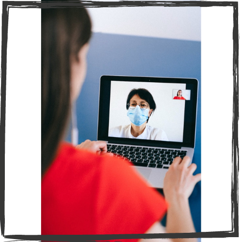 A woman w/long, black hair talks to a doctor on screen who wears glasses and a face mask